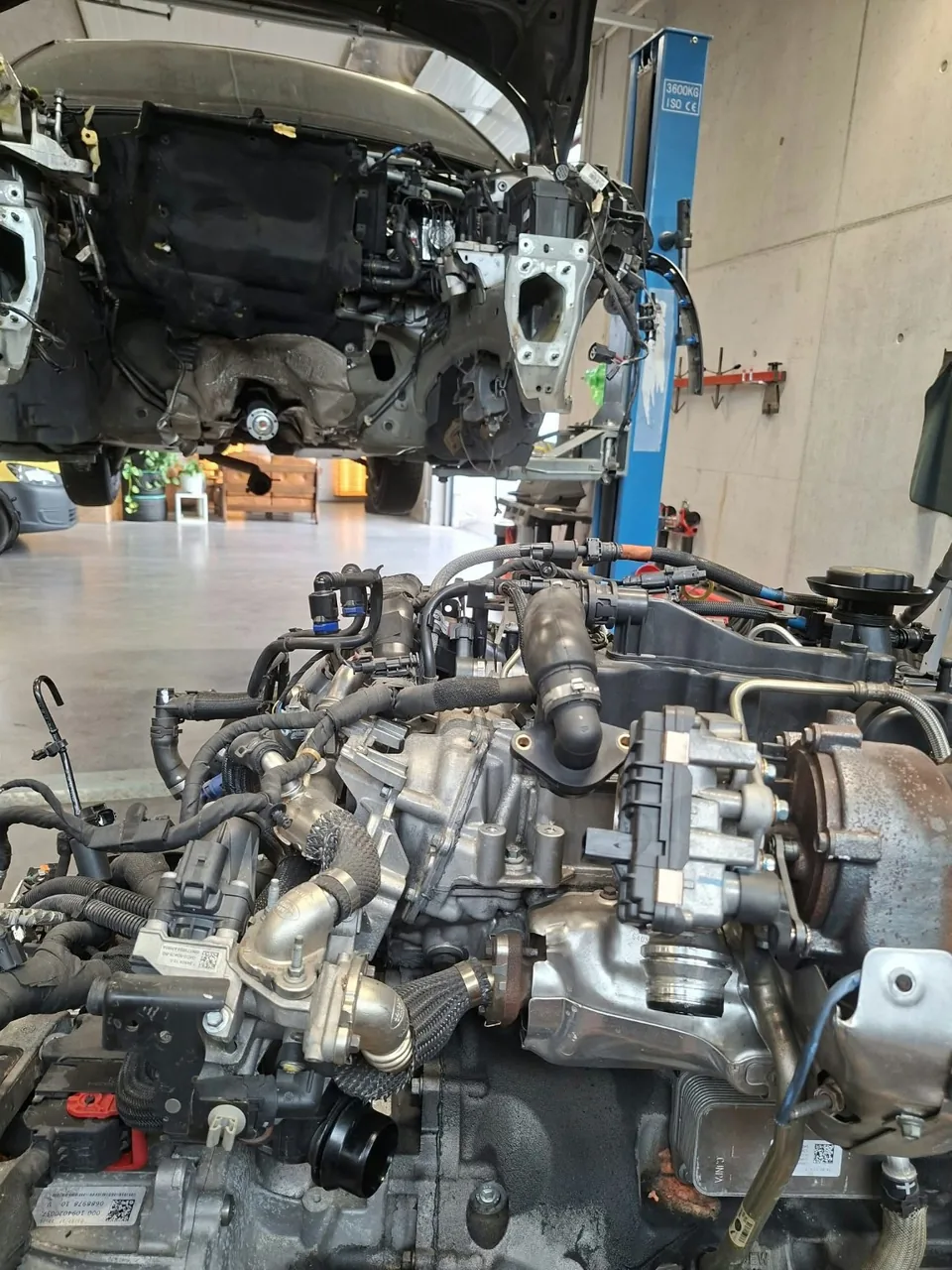 Ausgebauter Motor im Vordergrund, Fahrzeug auf der Hebebühne
