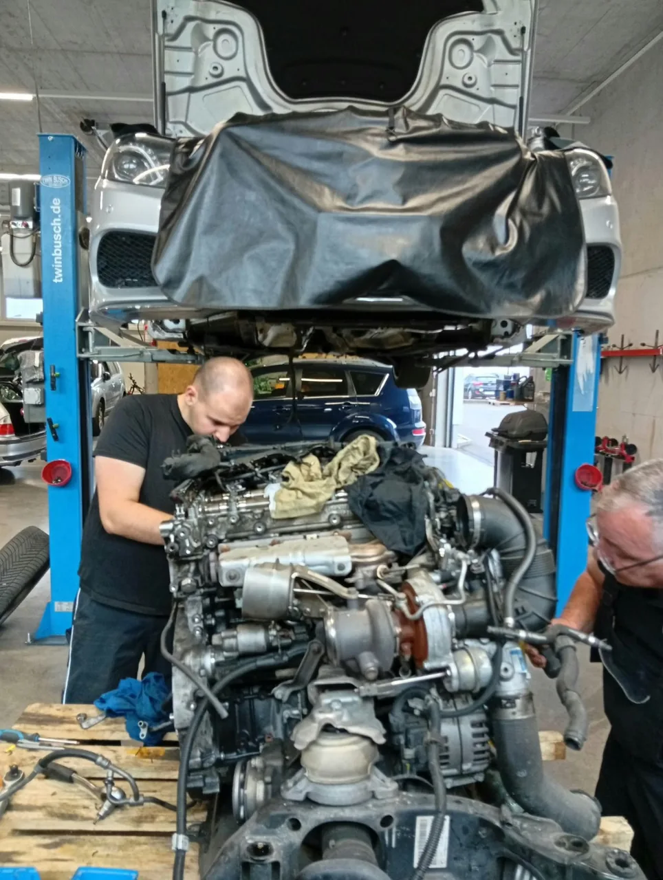 Werkstatt-Mitarbeiter bei Reparatur eines ausgebauten Motors