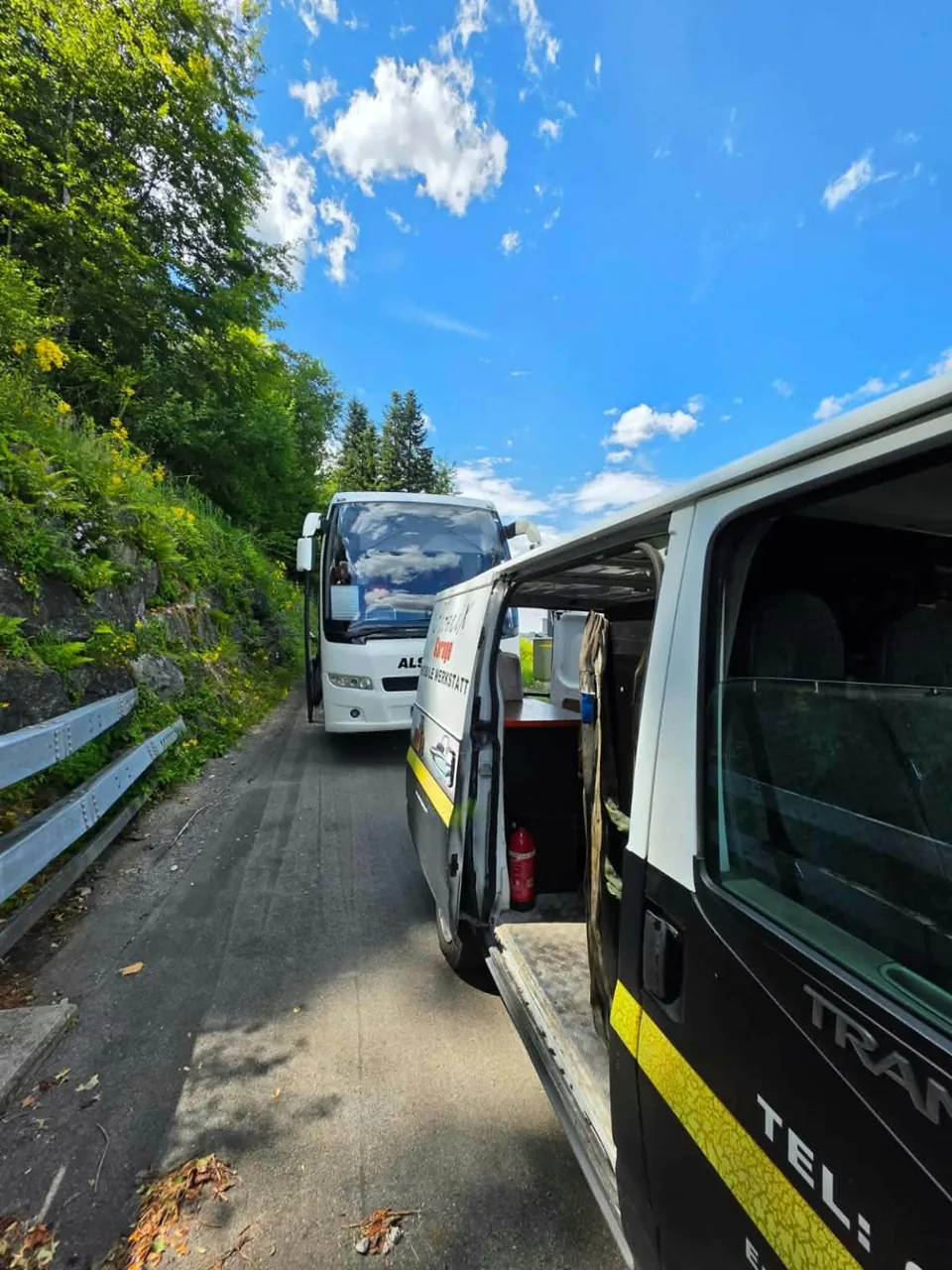 Werkstattfahrzeug mit geöffneter Seitentür und Bus im Hintergrund